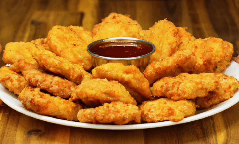 A plate of crispy chicken nuggets with a hot honey dip. A plate of crispy chicken nuggets with a hot honey dip.