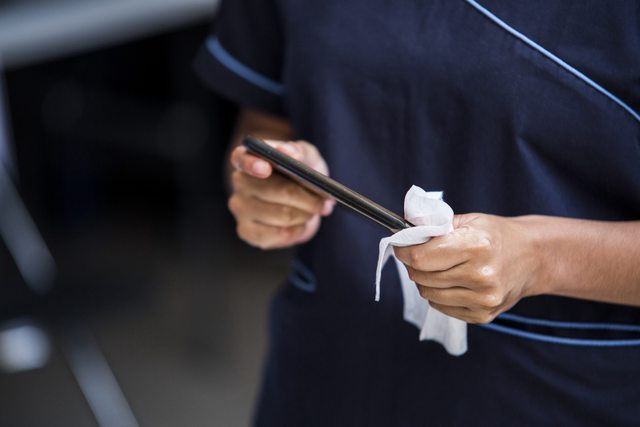 A person using a disinfectant wipe to clean an object. A person using a disinfectant wipe to clean an object.