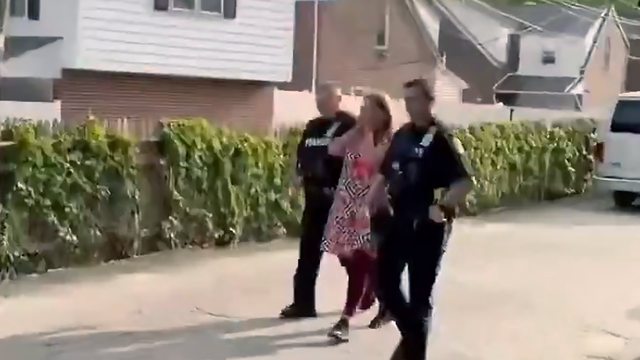 Two police officers walking with the woman charged with indecent exposure, disorderly conduct, criminal mischief, and depositing waste on a highway. Two police officers walking with the woman charged with indecent exposure, disorderly conduct, criminal mischief, and depositing waste on a highway.