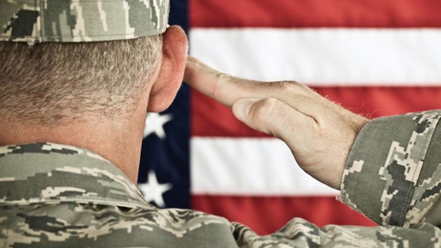 U.S. soldier salutes in front of the American flag. U.S. soldier salutes in front of the American flag.