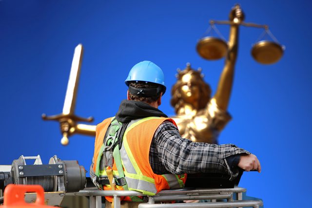 A construction worker in front of Lady Justice. A construction worker in front of Lady Justice.