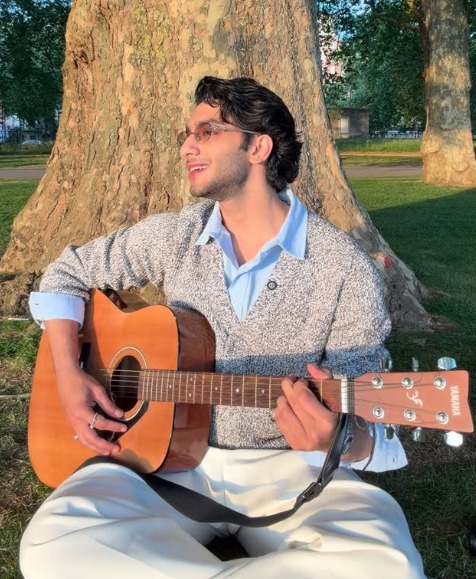 Vedang Rana playing guitar and singing Maskara under a tree in London Vedang Rana playing guitar and singing Maskara under a tree in London