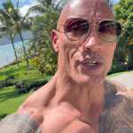 Dwayne Johnson wearing the Jumanji dice necklace prop on set Dwayne Johnson wearing the Jumanji dice necklace prop on set