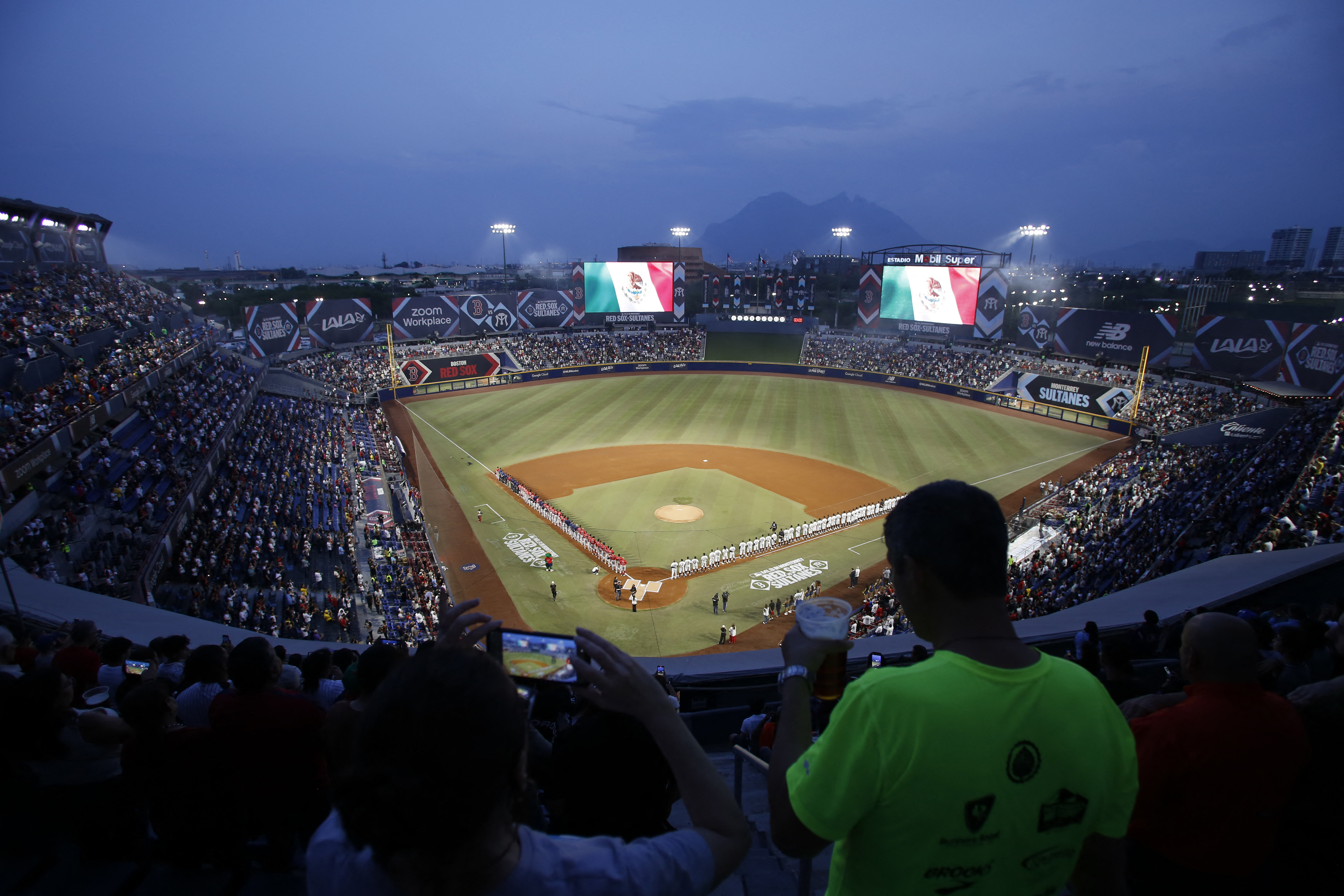 Players line the field for the national anthems before Monday's game. (Julio Cesar Aguilar/AFP via Getty Images)