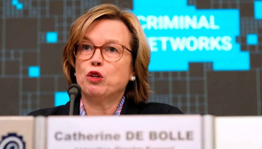 Catherine De Bolle, directora de Europol, hablando en un evento frente a un micrófono. Lleva gafas, un blazer oscuro y una blusa con un diseño discreto. Al fondo, se ve un cartel con las palabras "Criminal Networks" en letras grandes y un diseño tecnológico. Catherine De Bolle, directora de Europol, hablando en un evento frente a un micrófono. Lleva gafas, un blazer oscuro y una blusa con un diseño discreto. Al fondo, se ve un cartel con las palabras "Criminal Networks" en letras grandes y un diseño tecnológico.