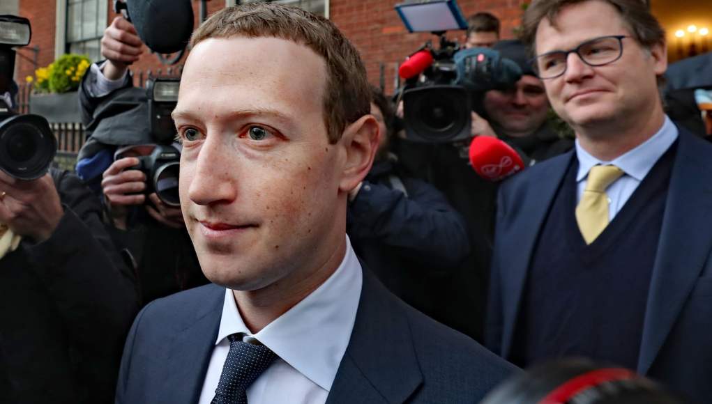 Un hombre vestido con traje y corbata camina entre un grupo de periodistas y fotógrafos que lo rodean con cámaras y micrófonos, mientras otra persona a su lado, también con traje y corbata, lo acompaña en la escena. Un hombre vestido con traje y corbata camina entre un grupo de periodistas y fotógrafos que lo rodean con cámaras y micrófonos, mientras otra persona a su lado, también con traje y corbata, lo acompaña en la escena.