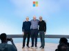 Microsoft posiciona la computación cuántica como próximo acelerador de la nube Tres figuras destacadas del mundo tecnológico posan sonrientes en un escenario con el logotipo de Microsoft al fondo. Están abrazados, en un ambiente amistoso, mientras el público los fotografía. La imagen transmite un momento simbólico dentro de un evento importante de la compañía.