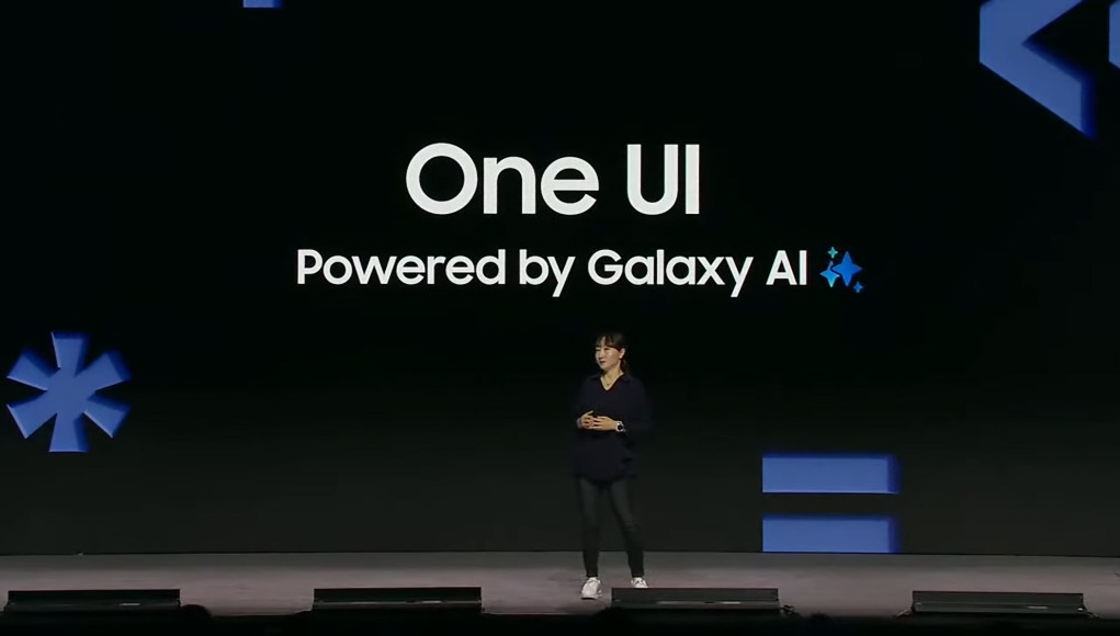 Sally Hyesoon Jeong en el escenario durante la conferencia de desarrolladores de 2024. En la pantalla detrás de ella aparece el texto "One UI Powered by Galaxy AI", destacando el enfoque de Samsung en la integración de inteligencia artificial en su interfaz de usuario. La presentación se lleva a cabo en un entorno oscuro, con gráficos en tonos azules y minimalistas a los lados del escenario, y la presentadora está vestida de manera casual. Sally Hyesoon Jeong en el escenario durante la conferencia de desarrolladores de 2024. En la pantalla detrás de ella aparece el texto "One UI Powered by Galaxy AI", destacando el enfoque de Samsung en la integración de inteligencia artificial en su interfaz de usuario. La presentación se lleva a cabo en un entorno oscuro, con gráficos en tonos azules y minimalistas a los lados del escenario, y la presentadora está vestida de manera casual.
