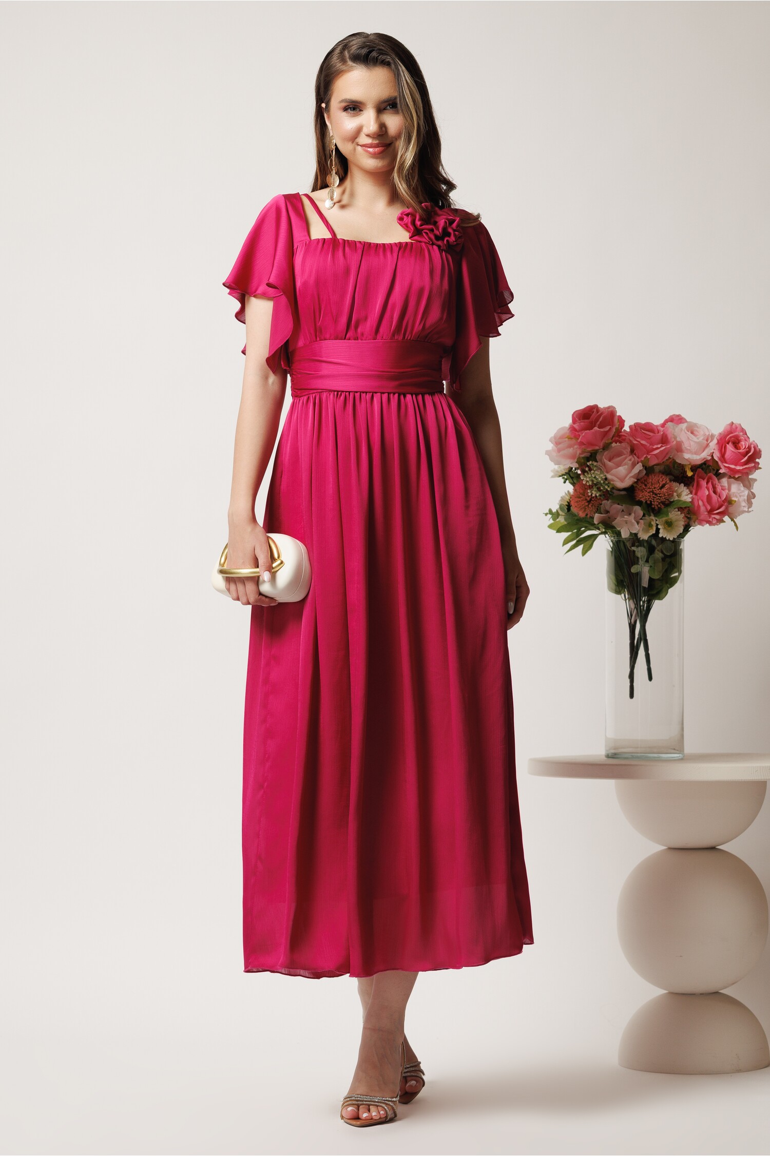 Rochie lungă fucsia în cloș din voal cu floare la bust Rochie lungă fucsia în cloș din voal cu floare la bust