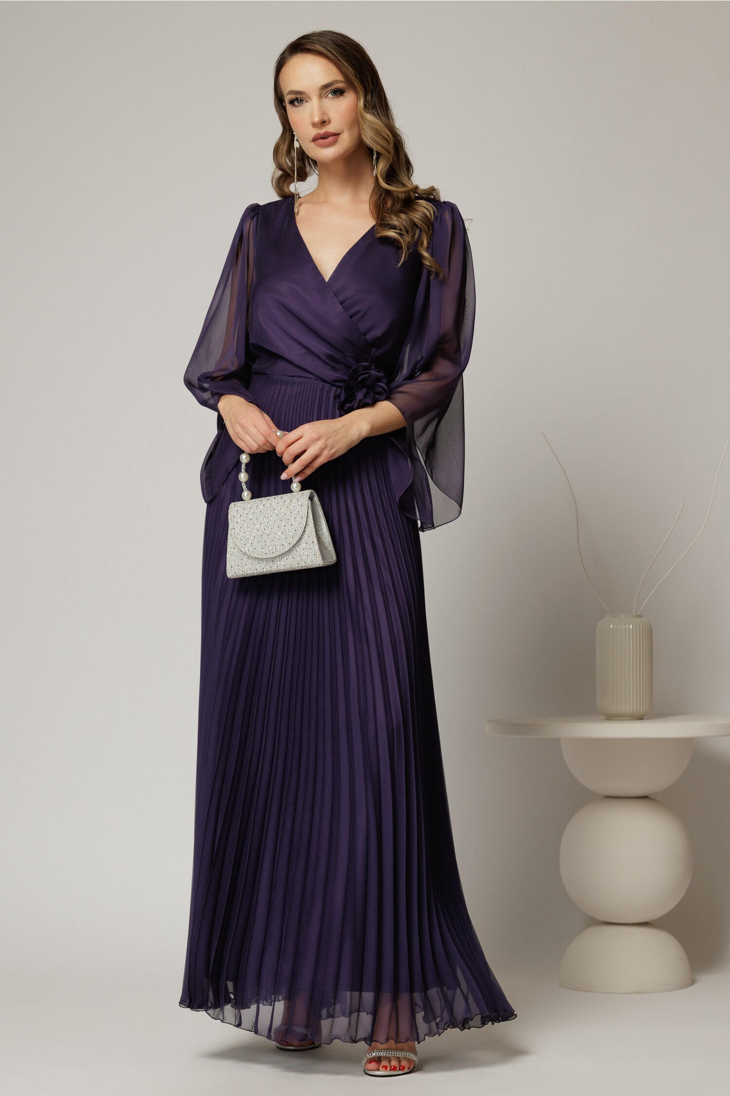 Rochie lungă mov elegantă de ocazie cu fustă plisată și floare în talie Rochie lungă mov elegantă de ocazie cu fustă plisată și floare în talie
