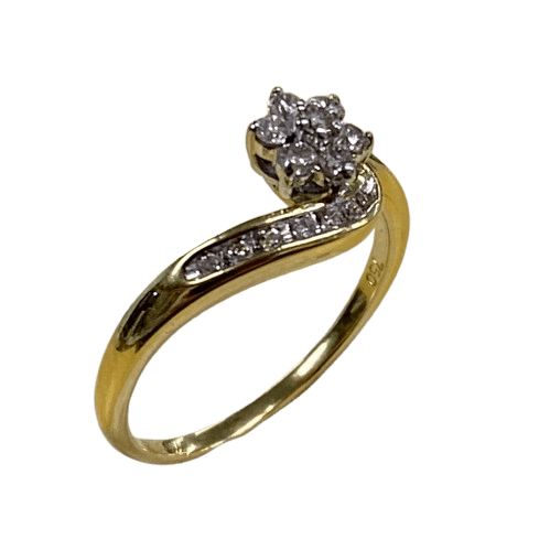 Ladies 18ct White & Yellow Gold 14 Stone Diamond Ring. Round Brilliant Cut White Gold 6 Claw Set Centre Stone Surrounded By 6 Round Brilliant Cut White Gold Claw Set Forming A Cluster. With 7 Brilliant Cut Diamonds Channel Set In Wrap Around Shoulder. TDW 0.26ct. Size R/9, With Valuation Certificate – (NG 147229)