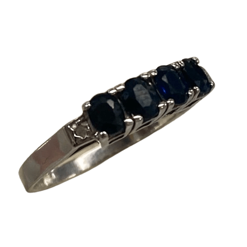 Ladies 9ct White Gold 6 Stone Sapphire & Diamond Ring. 4 Oval Sapphires, 4 Claw Set. With 2 Square Grain Set Diamonds In Swept Up Shoulders. TDW 1.15ct. Size P/8 . With Valuation Certificate – (NG 73254)
