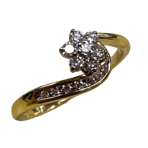 Ladies 18ct White & Yellow Gold 14 Stone Diamond Ring. Round Brilliant Cut White Gold 6 Claw Set Centre Stone Surrounded By 6 Round Brilliant Cut White Gold Claw Set Forming A Cluster. With 7 Brilliant Cut Diamonds Channel Set In Wrap Around Shoulder. TDW 0.26ct. Size R/9, With Valuation Certificate – (NG 147229)
