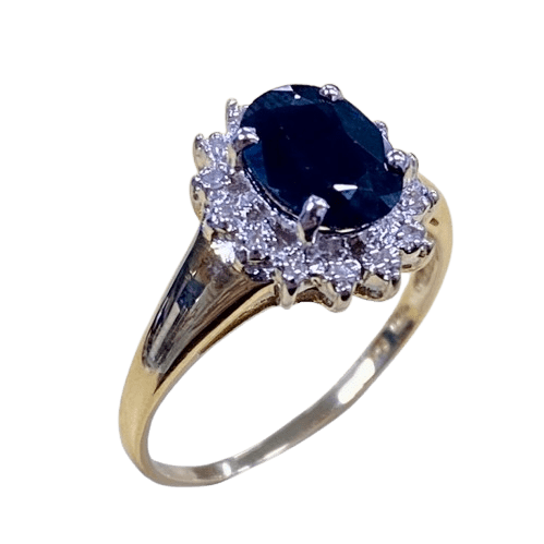 Ladies 9ct Yellow Gold 15 Stone Diamond & Sapphire Ring. Oval Sapphire In Rhodium 4 Claw Setting, Surrounded by 14 Single Cut Diamonds Illusion Bead Set in Rhodium Plated Basket, In Swept Up Shoulders. TDW 0.07ct. Size M/6.5, With Valuation Certificate – (NG 1307520)