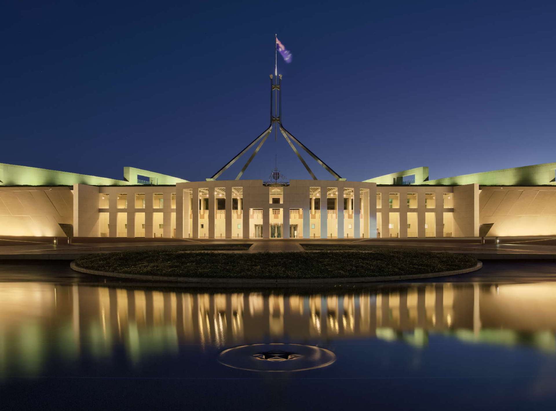 A stunning view of the Parliament House in Canberra, showcasing its modern architecture against a clear blue sky. A stunning view of the Parliament House in Canberra, showcasing its modern architecture against a clear blue sky.
