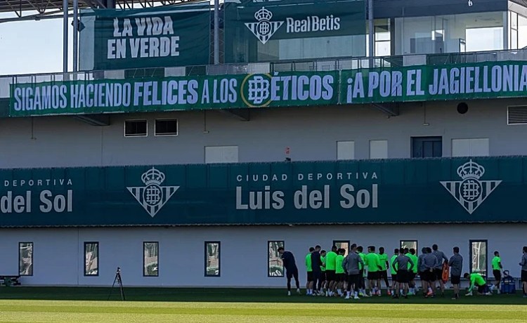 La pancarta en la ciudad deportiva del Betis: «Sigamos haciendo felices a los béticos; ¡a por el Jagiellonia!» La pancarta en la ciudad deportiva del Betis: «Sigamos haciendo felices a los béticos; ¡a por el Jagiellonia!»
