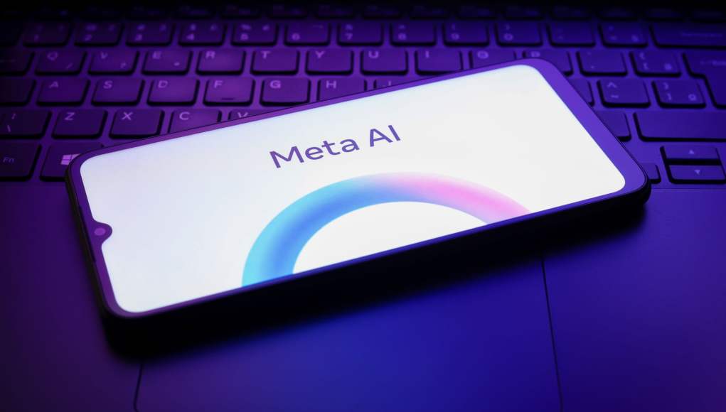 Teléfono móvil con la pantalla encendida mostrando el logotipo de 'Meta AI', colocado sobre un teclado de computadora iluminado con luces de color púrpura, creando un ambiente tecnológico y moderno. Teléfono móvil con la pantalla encendida mostrando el logotipo de 'Meta AI', colocado sobre un teclado de computadora iluminado con luces de color púrpura, creando un ambiente tecnológico y moderno.