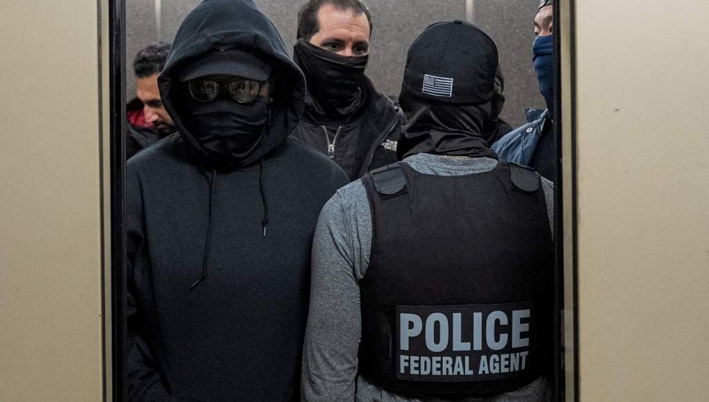 Un grupo de agentes federales, vestidos con ropa oscura y mascarillas que cubren sus rostros, se encuentra dentro de un ascensor. Uno de ellos, de espaldas, lleva un chaleco con la palabra “POLICE – FEDERAL AGENT”. La escena transmite una operación policial encubierta o de alto riesgo. Un grupo de agentes federales, vestidos con ropa oscura y mascarillas que cubren sus rostros, se encuentra dentro de un ascensor. Uno de ellos, de espaldas, lleva un chaleco con la palabra “POLICE – FEDERAL AGENT”. La escena transmite una operación policial encubierta o de alto riesgo.