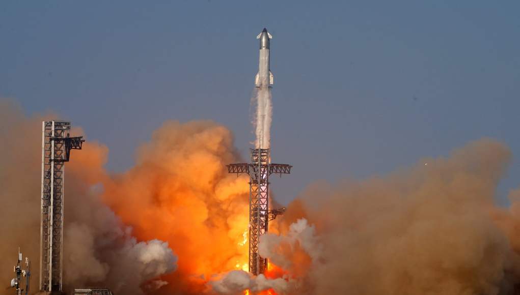 Cohete espacial despegando desde una plataforma de lanzamiento, rodeado de una intensa nube de humo y fuego en la base, mientras asciende verticalmente hacia el cielo despejado Cohete espacial despegando desde una plataforma de lanzamiento, rodeado de una intensa nube de humo y fuego en la base, mientras asciende verticalmente hacia el cielo despejado