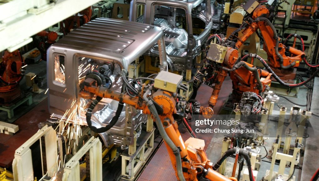 Robots industriales automatizados ensamblando carrocerías de vehículos en una línea de producción dentro de una fábrica. Chispas visibles mientras las máquinas realizan soldadura y tareas de ensamblaje. Robots industriales automatizados ensamblando carrocerías de vehículos en una línea de producción dentro de una fábrica. Chispas visibles mientras las máquinas realizan soldadura y tareas de ensamblaje.