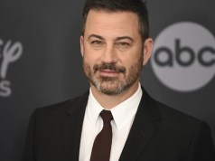 Disney+ colapsa mientras usuarios huyen en masa tras la suspensión de Kimmel Hombre con barba y cabello corto vestido con traje oscuro, camisa blanca y corbata burdeos, posando frente a un fondo con logotipos de Disney y ABC.