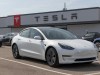 Decenas de miles de Tesla llamados a revisión por un peligroso ‘defecto de fábrica’ Tesla Model 3 blanco estacionado frente a una tienda de Tesla. La tienda tiene un cartel grande con el logo de Tesla y su nombre en la fachada. Otros vehículos Tesla están aparcados alrededor del Model 3, que está en primer plano y bien iluminado por la luz del día.