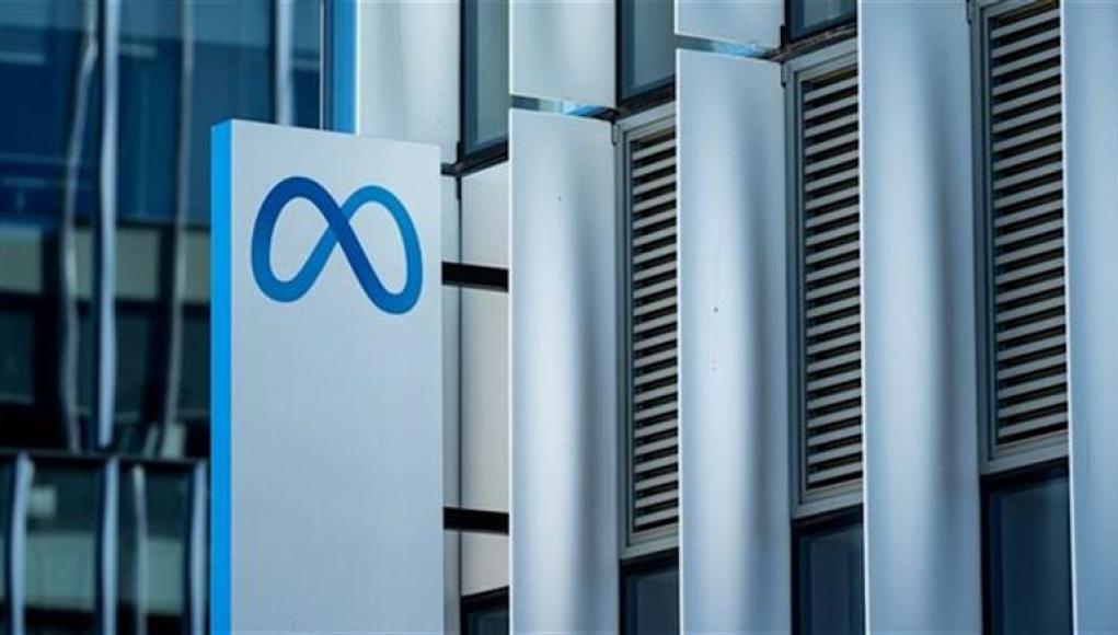 Primer plano de un cartel con el logotipo de Meta (símbolo de infinito estilizado en azul) frente a la fachada moderna de un edificio de oficinas, con paneles metálicos verticales y ventanas acristaladas. Primer plano de un cartel con el logotipo de Meta (símbolo de infinito estilizado en azul) frente a la fachada moderna de un edificio de oficinas, con paneles metálicos verticales y ventanas acristaladas.