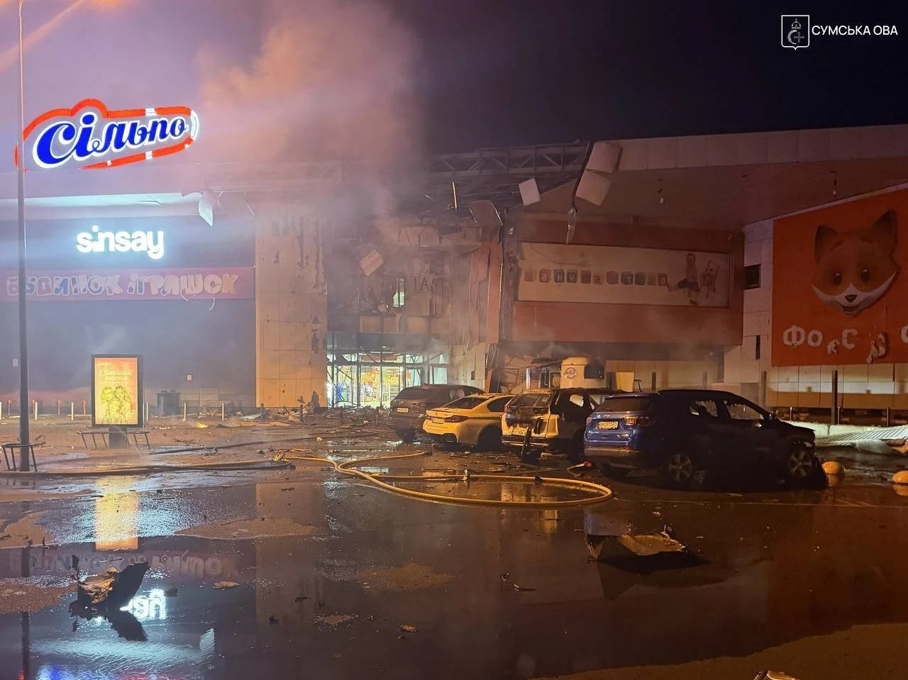 Pompieri sting flăcări în parcarea centrului comercial Sumi după atac rusesc drone, cu victime atac drone și mașini avariate pe asfalt. | sursa foto: Adevarul Pompieri sting flăcări în parcarea centrului comercial Sumi după atac rusesc drone, cu victime atac drone și mașini avariate pe asfalt. | sursa foto: Adevarul