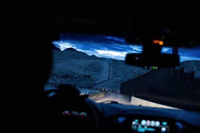 A man is halted climbing the US-Mexico border wall. Under new Trump rules, US troops sound the alarm