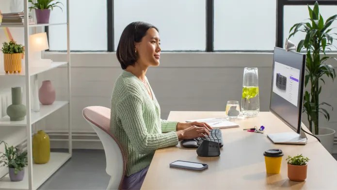 Persona sentada en el escritorio usando el teclado Wave Keys y el ratón ergonómico Lift