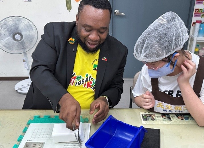 聖克里斯多福及尼維斯聯邦大使參訪唐氏症基金會 推動跨國交流 4 %E5%9C%96%EF%BC%9A%E5%A4%A7%E4%BD%BF%E8%8C%83%E6%9D%B1%E4%BA%9E%E9%AB%94%E9%A9%97%E6%89%8B%E5%B7%A5%E7%9A%82%E8%A3%BD%E4%BD%9C%EF%BC%8C%E5%B1%95%E7%8F%BE%E5%B0%8D%E5%85%AC%E7%9B%8A%E7%9A%84%E6%94%AF%E6%8C%81%E3%80%82