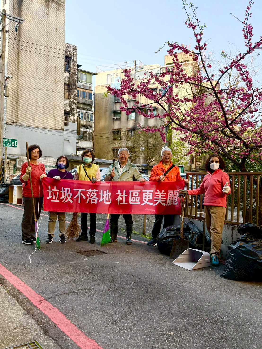 六合志工櫻花下宣導「垃圾不落地、社區更美麗」 2 圖為蔡志峰前理事長(右三)率六合志工清掃環境乾淨家園,並於美麗的櫻花下宣導「垃圾不落地、社區更美麗」/六合志工提供