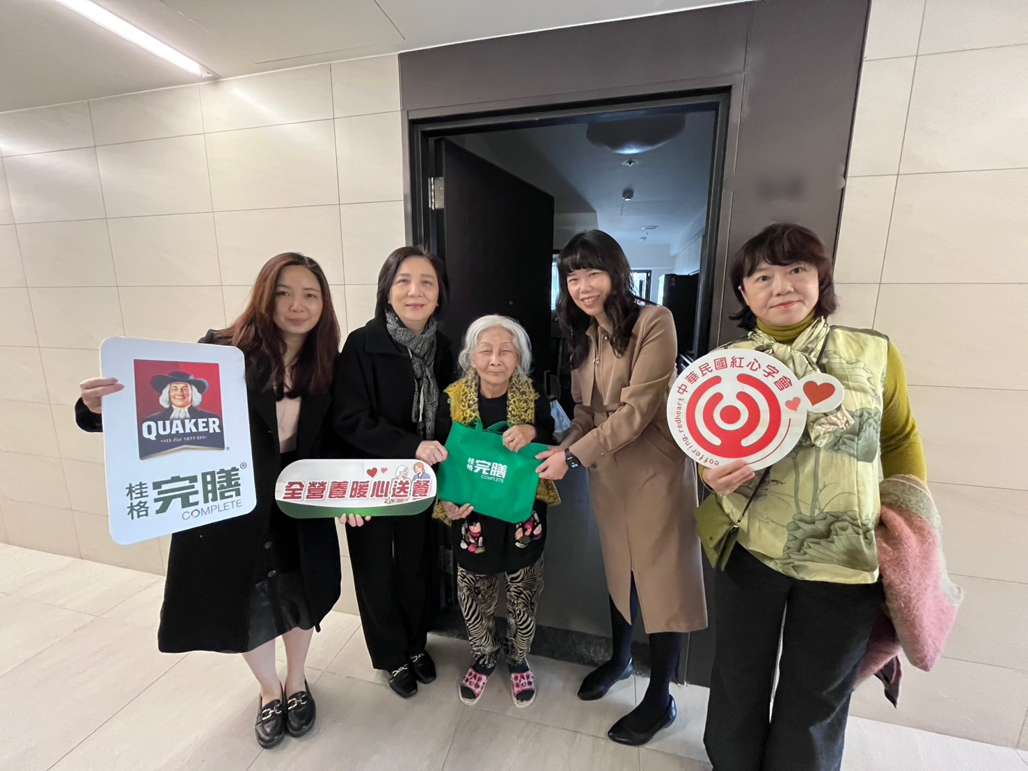 暖心送餐不打烊!佳格攜手紅心字會啟動「全營養應援計畫」守護樂齡的營養 左起-產品組經理楊久盈、紅心字會李顯文秘書長、社宅91歲獨居余奶奶、資深行銷經理潘雨青、紅心字會許雅青副秘書長,將全營養軟質餐暖心送到府!(圖/紅心字會 提供)