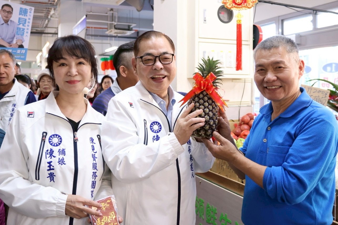 文創紅包掀市場旋風!「陳見賢拋產業交通長照藍圖」世代共好成選戰主軸 新竹縣長參選人陳見賢於市場拜年時,攤商送上象徵「旺來」的鳳梨祝福好彩頭,現場氣氛熱絡。(圖/記者林照東翻攝)