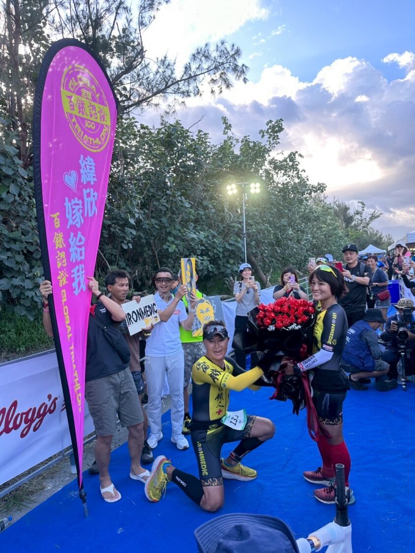 全球首見!百朵樂高玫瑰現身鐵人終點 醫護鐵人創辦人陳彥良浪漫求婚成功 | 索引新聞 INDEX News 陳彥良手捧百朵樂高玫瑰花,於終點拱門下單膝跪地,向洪緯欣深情告白,全場掌聲與歡呼不絕於耳。(圖/記者張家燁翻攝)