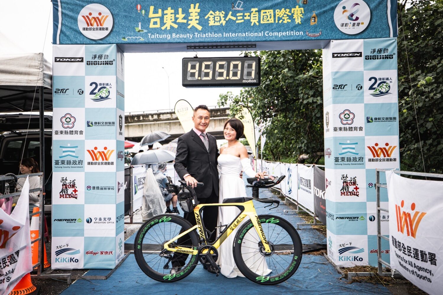 全球首見!百朵樂高玫瑰現身鐵人終點 醫護鐵人創辦人陳彥良浪漫求婚成功 | 索引新聞 INDEX News 陳彥良(左)與洪緯欣(右)身穿西裝與白紗於終點拱門前合影,象徵鐵人終點即是愛情起點。(圖/記者張家燁翻攝)