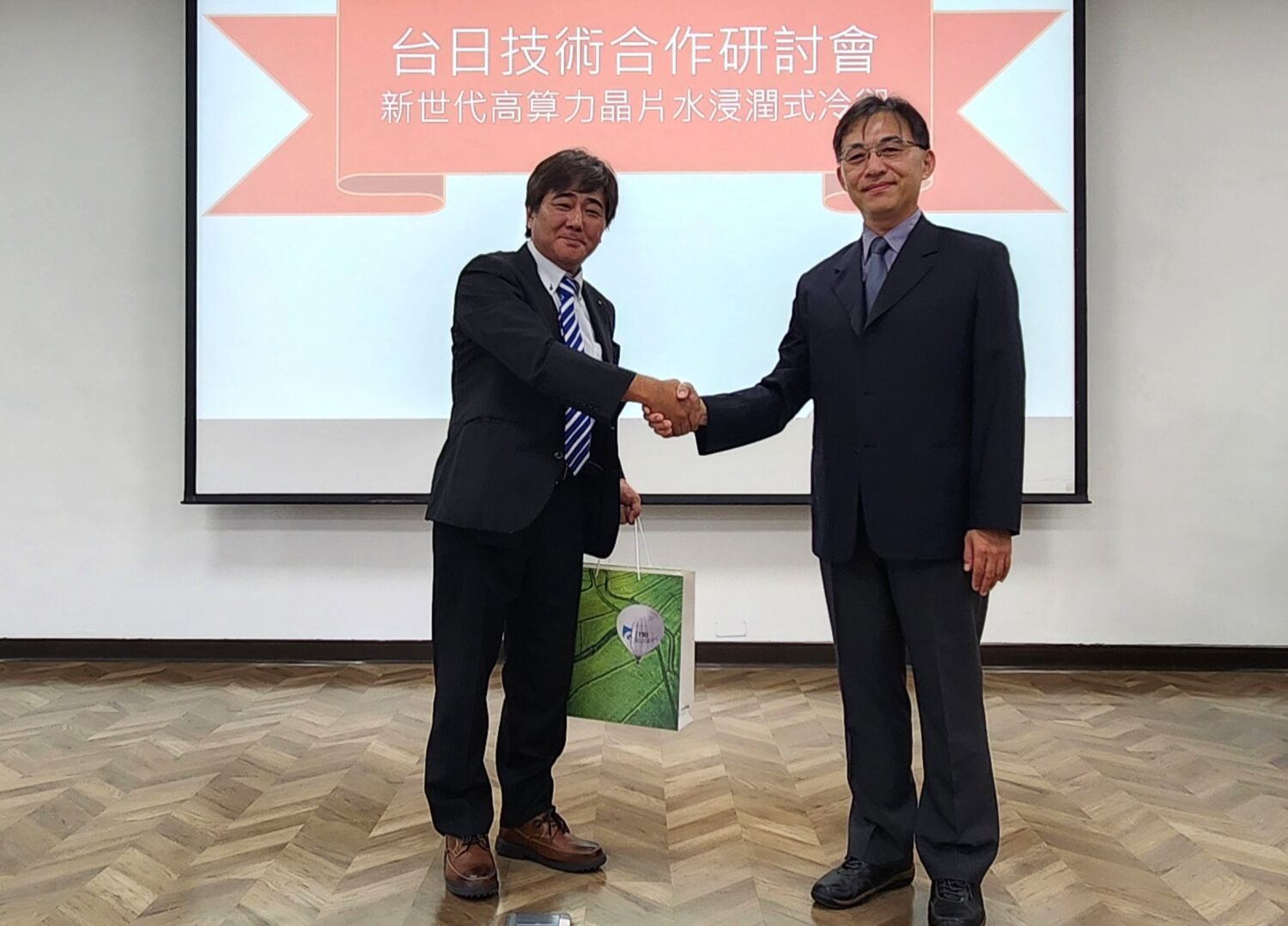 工研院攜手日本新創ZYRQ 開發全球首創水浸潤式冷卻技術 台日最新合作開發「水浸潤式冷卻技術」,可解決AI晶片高功耗造成的散熱瓶頸。左為日本ZYRQ社長長井大、右為工研院機械所副所長楊秉祥。(圖/記者黃溎芬翻攝)