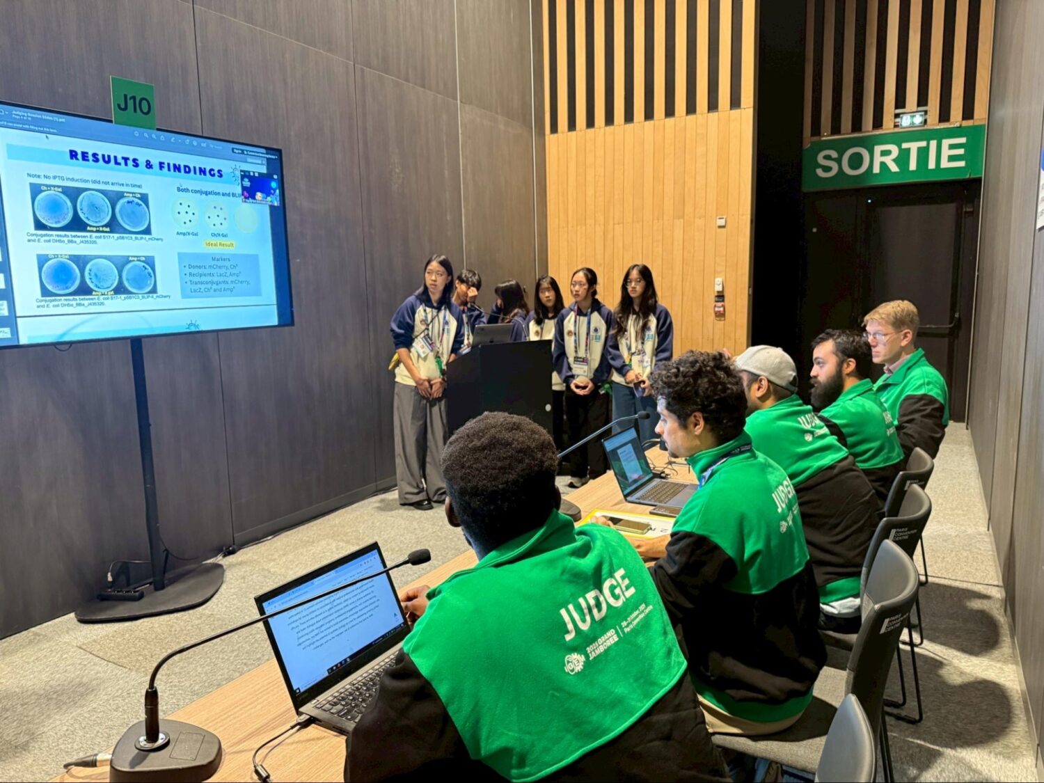 臺灣之光!HIA學生團隊以抗藥性創新研究奪下iGEM金牌榮耀 HIA-Taiwan PlasMission 團隊於 iGEM Grand Jamboree 現場向國際評審進行研究簡報,展現自主實驗成果與合成生物學應用構想。(圖/記者張家燁翻攝)