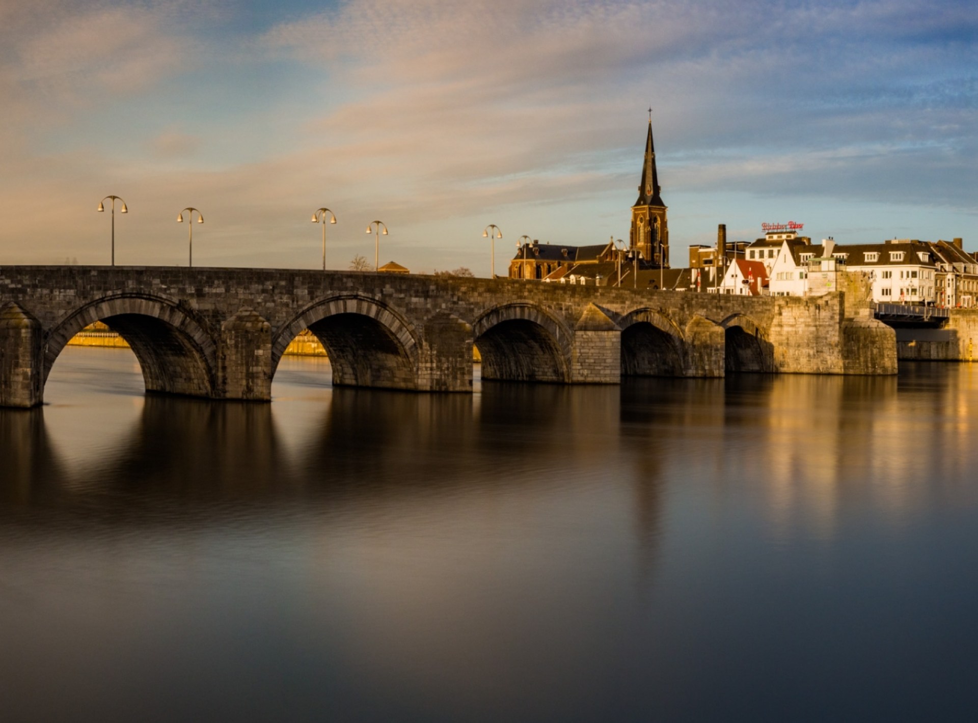 St. Servatius Bridge illuminated at night in Maastricht, showcasing its historical architecture and serene river views. St. Servatius Bridge illuminated at night in Maastricht, showcasing its historical architecture and serene river views.