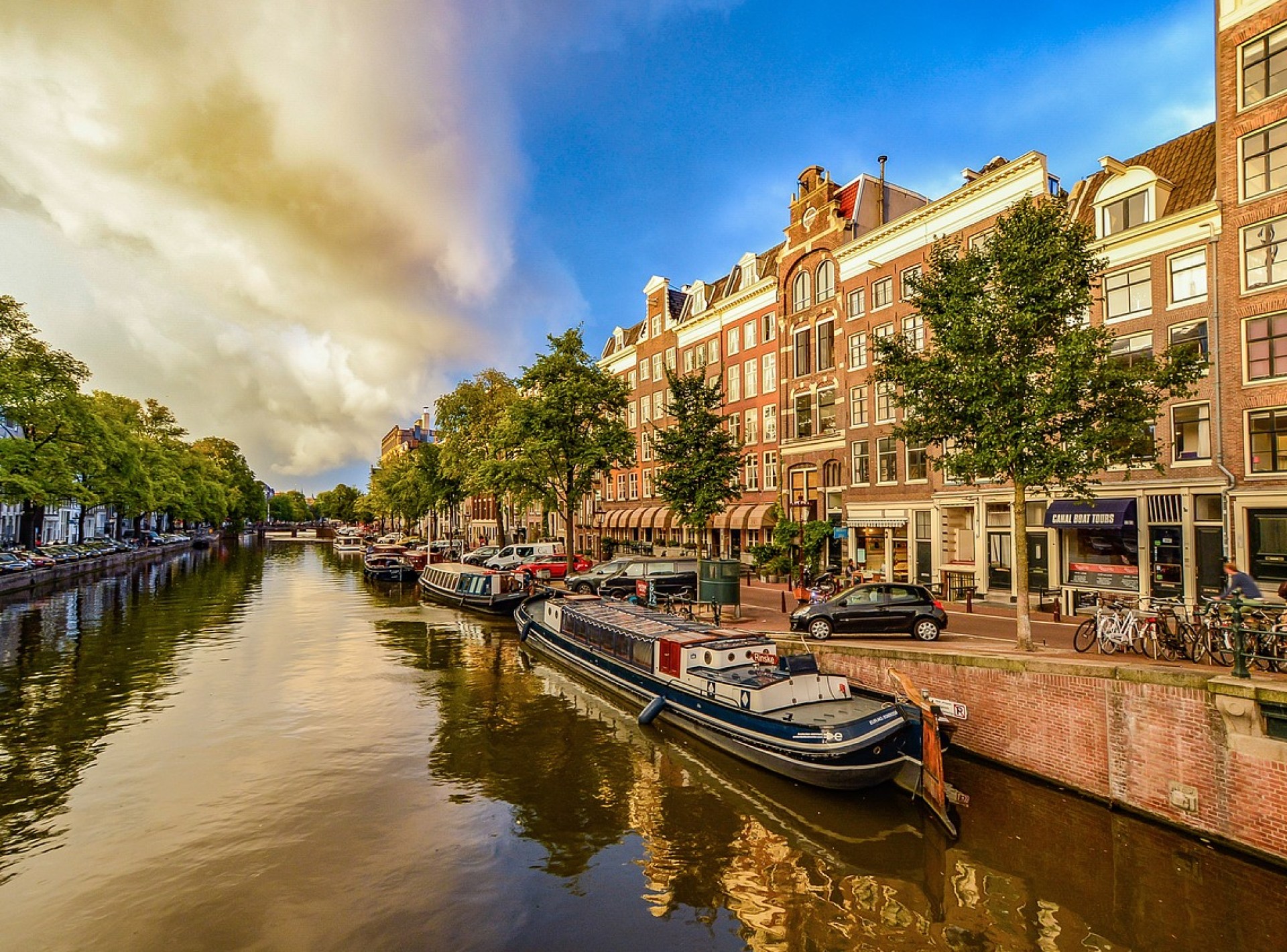Scenic view of Amsterdam's iconic canals surrounded by historic buildings and lush greenery, capturing the city's charming atmosphere. Scenic view of Amsterdam's iconic canals surrounded by historic buildings and lush greenery, capturing the city's charming atmosphere.