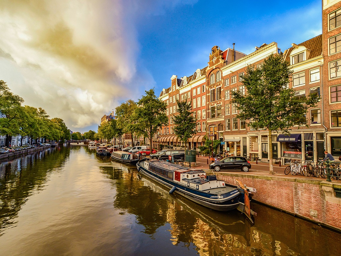 Beautiful view of Amsterdam's iconic canals lined with vibrant buildings and lush greenery under a clear blue sky. Beautiful view of Amsterdam's iconic canals lined with vibrant buildings and lush greenery under a clear blue sky.