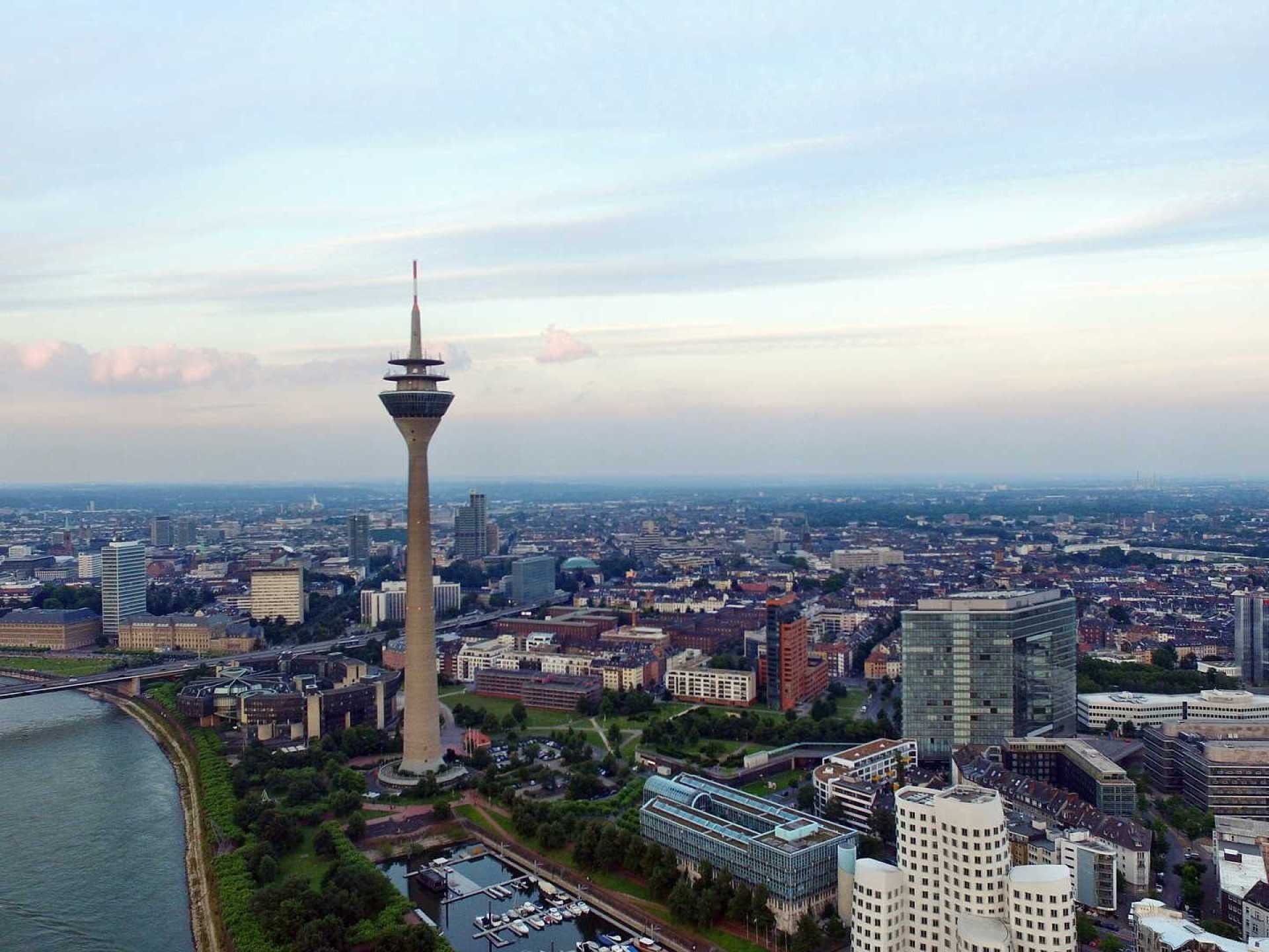 A panoramic view of Dusseldorf's iconic Rheinturm tower against a clear blue sky. A panoramic view of Dusseldorf's iconic Rheinturm tower against a clear blue sky.