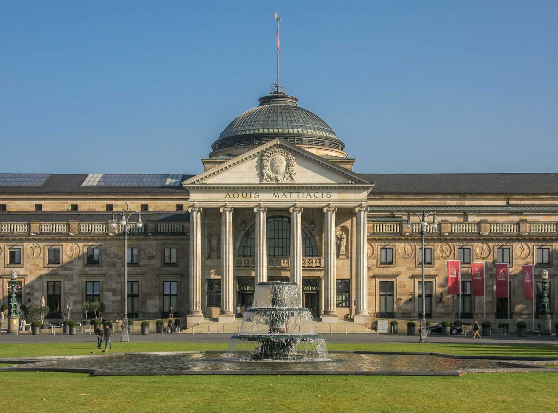 Exterior view of the Kurhaus in Wiesbaden, showcasing its elegant architecture and beautiful landscaped gardens. Exterior view of the Kurhaus in Wiesbaden, showcasing its elegant architecture and beautiful landscaped gardens.