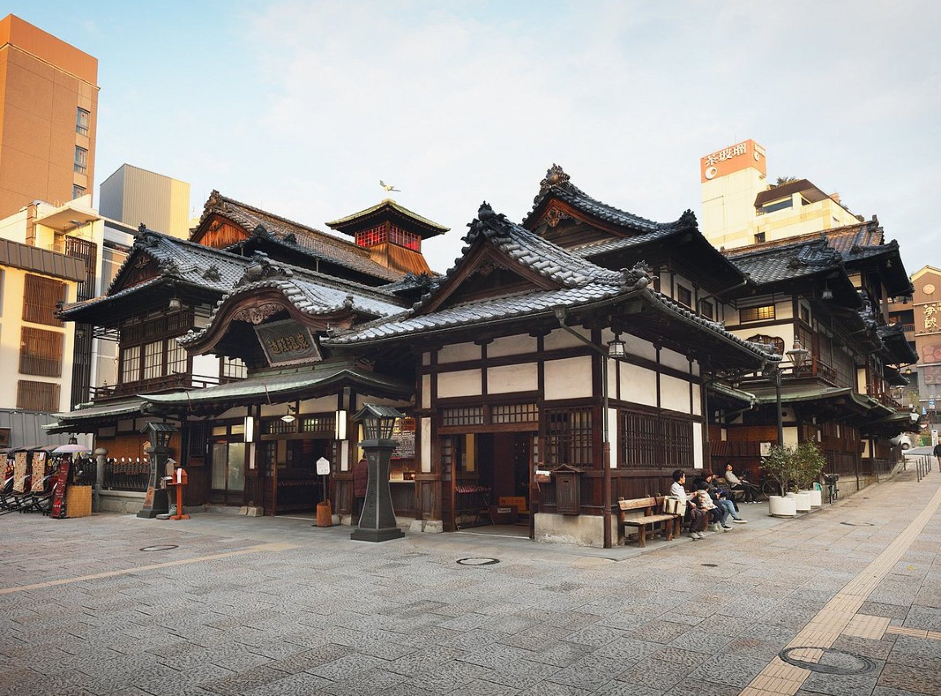 Relaxing hot springs at Dogo Onsen in Matsuyama, Japan, with traditional architecture and lush greenery surrounding the spa. Relaxing hot springs at Dogo Onsen in Matsuyama, Japan, with traditional architecture and lush greenery surrounding the spa.