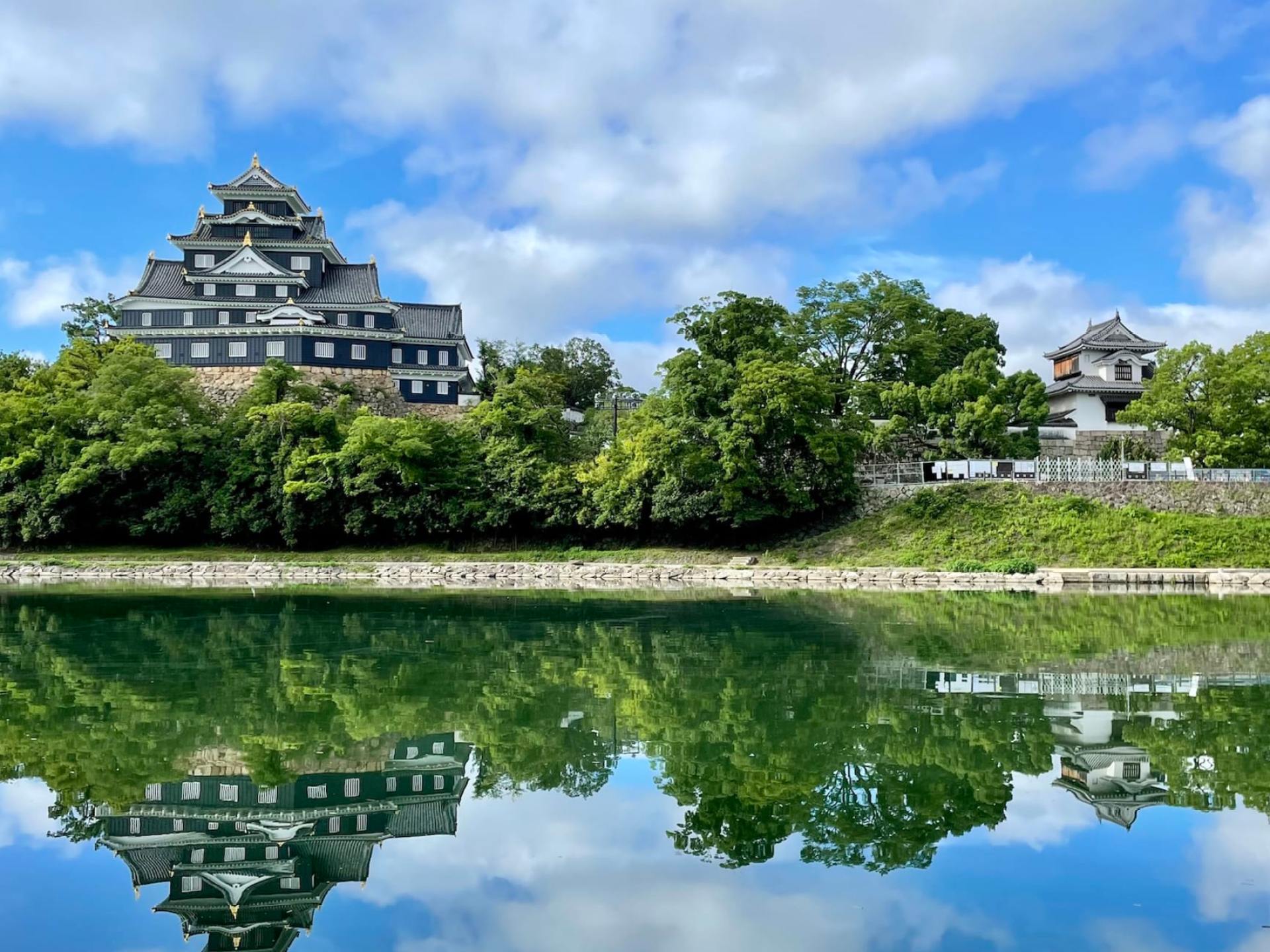 Alt text for the image: Scenic view of Okayama Castle surrounded by lush greenery and a clear blue sky in Okayama, Japan. Alt text for the image: Scenic view of Okayama Castle surrounded by lush greenery and a clear blue sky in Okayama, Japan.