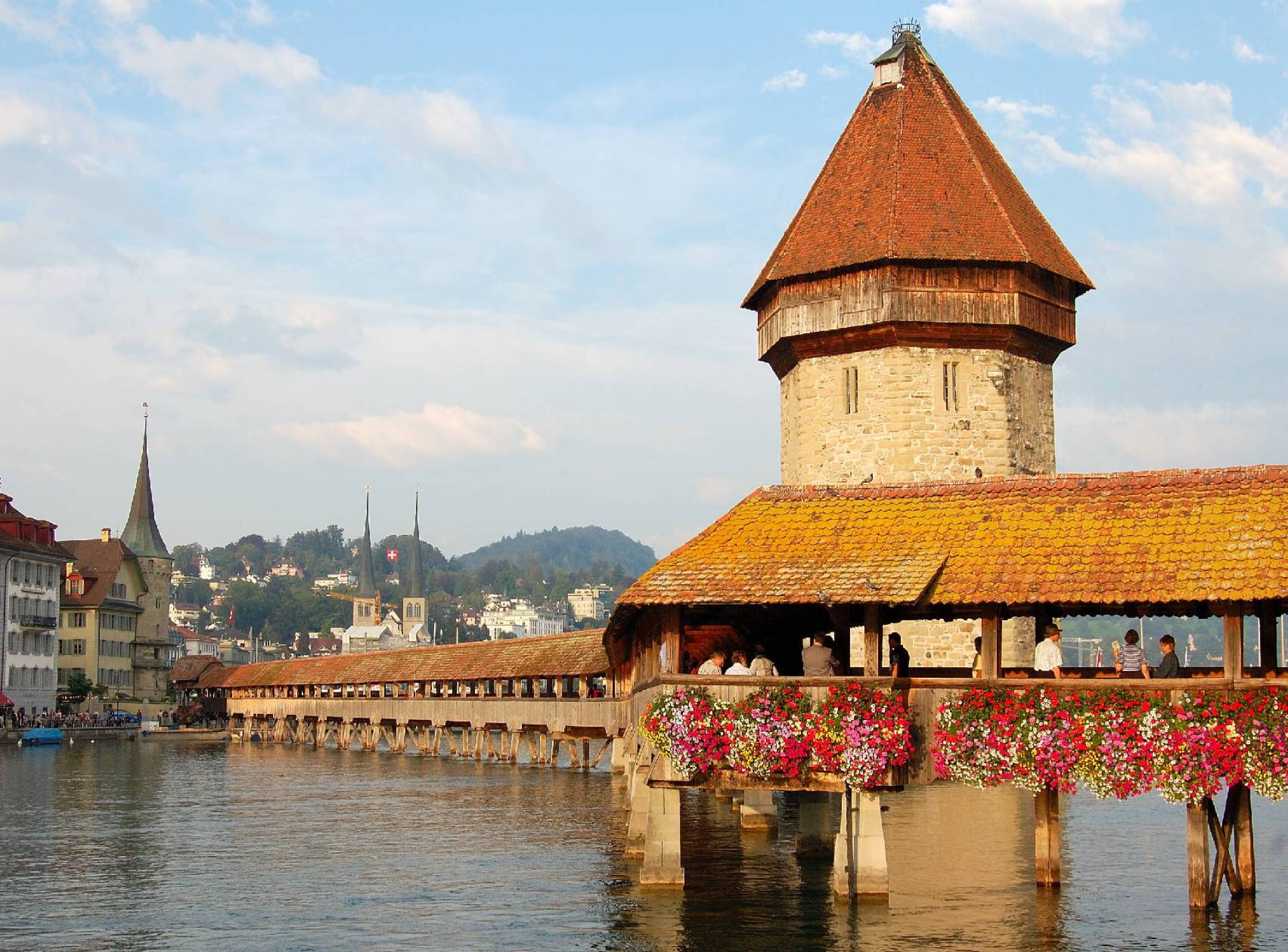 A scenic view of Lucerne's iconic Chapel Bridge, showcasing its historic wooden architecture against the tranquil waters. A scenic view of Lucerne's iconic Chapel Bridge, showcasing its historic wooden architecture against the tranquil waters.