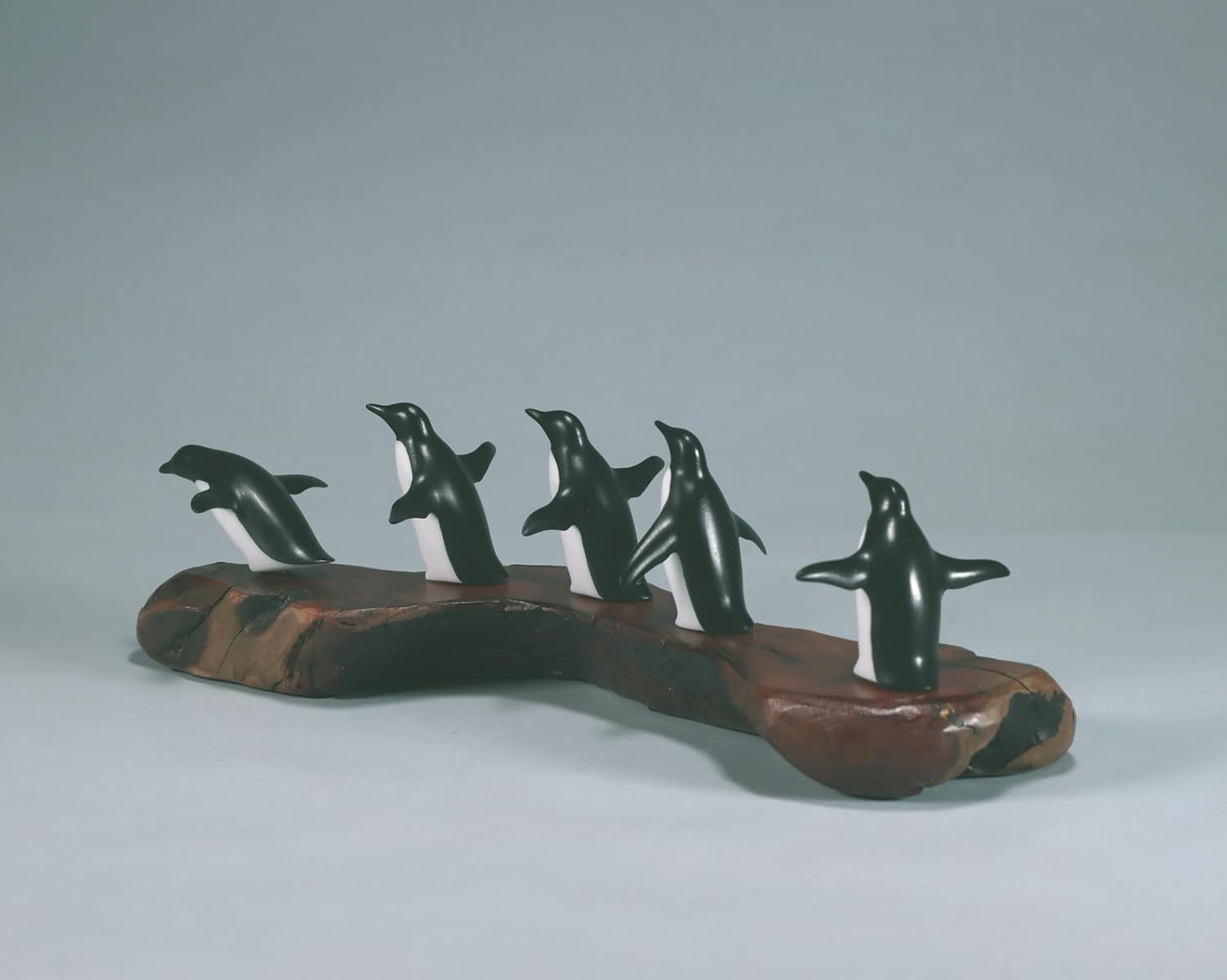 Penguin flock of 5 sculpture by John Perry approx 11 inches long on burl base