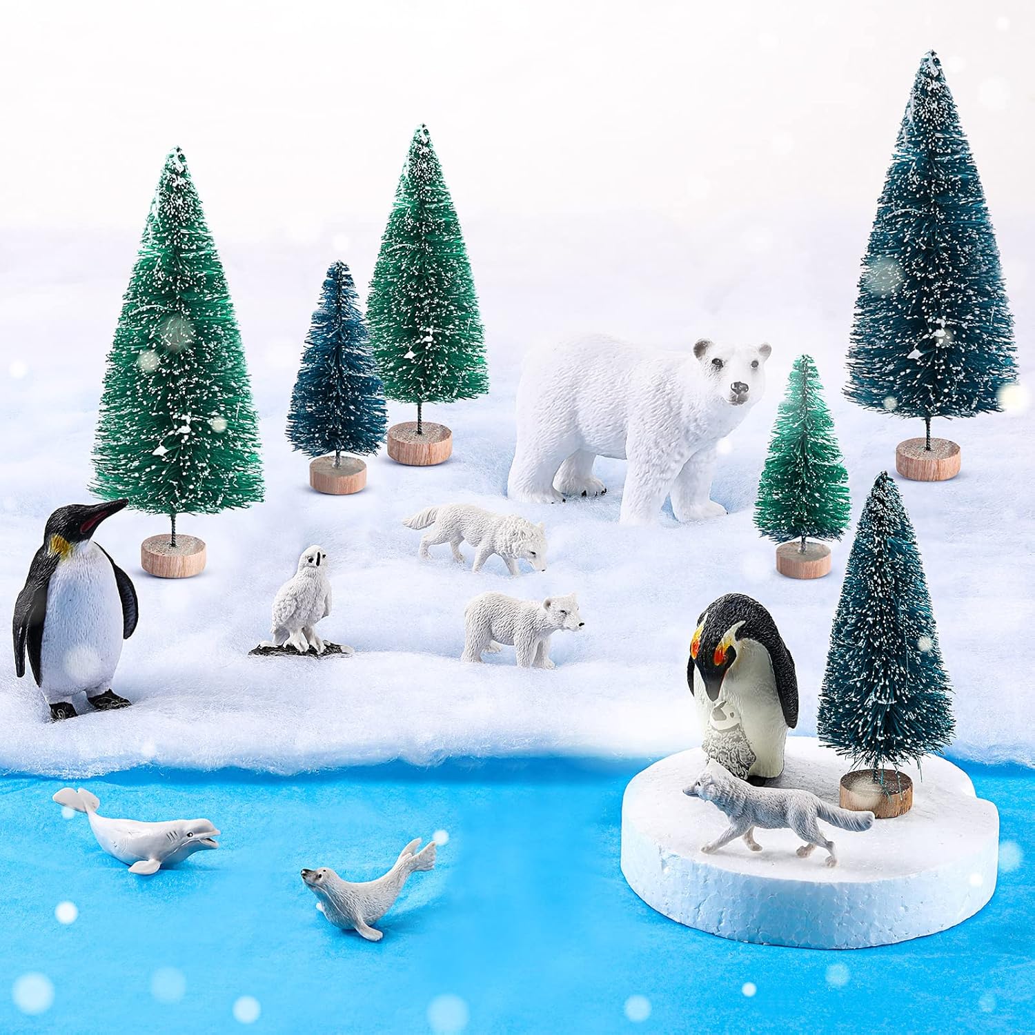El juego de 19 juguetes de animales árticos incluye 10 figuras de animales polares, 6 pinos en miniatura, 1 tabla de espuma, 1 manta de nieve falsa