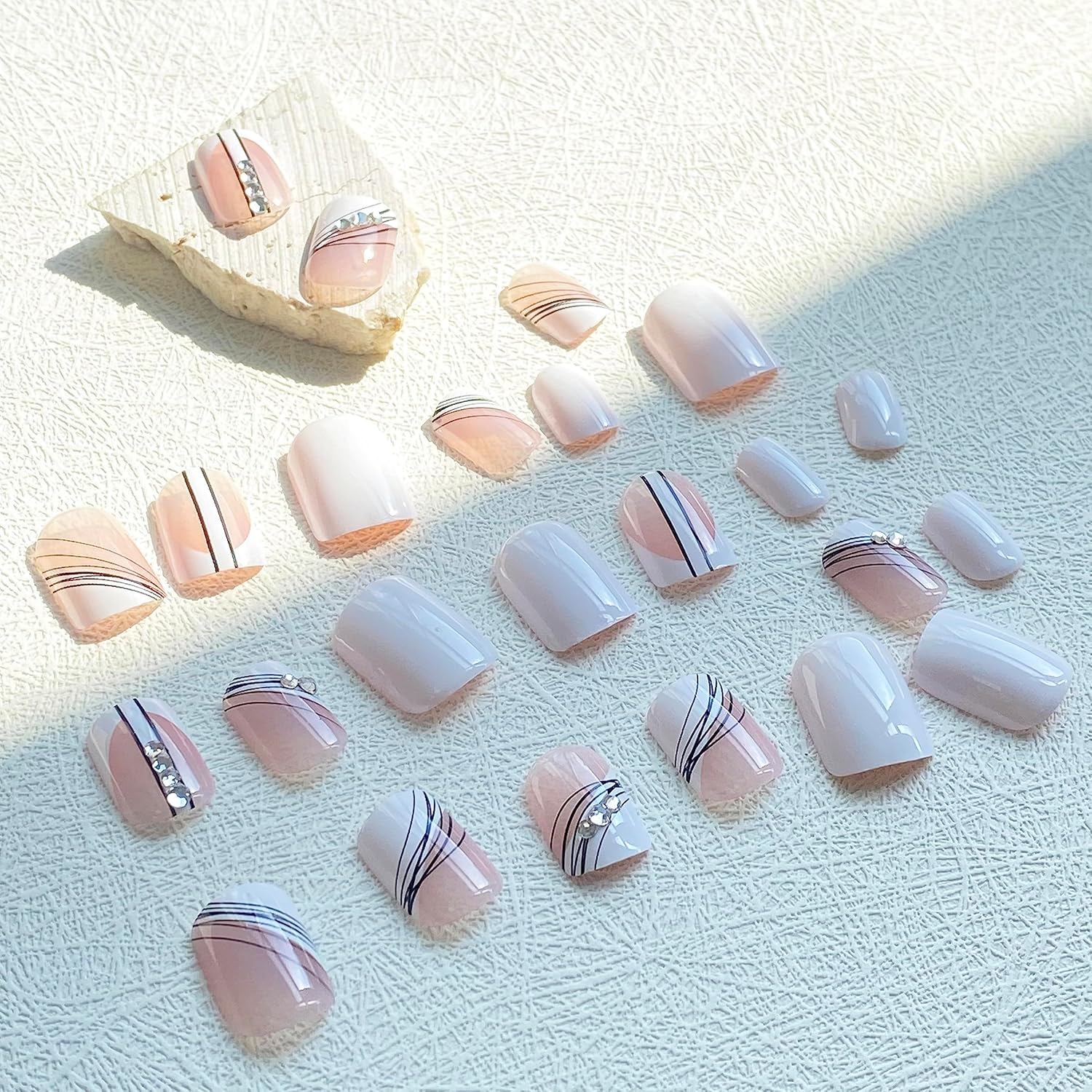 Uñas postizas a presión de punta francesa medianas con diseños de líneas negras, uñas adhesivas con diamantes de imitación blanco nude crema con