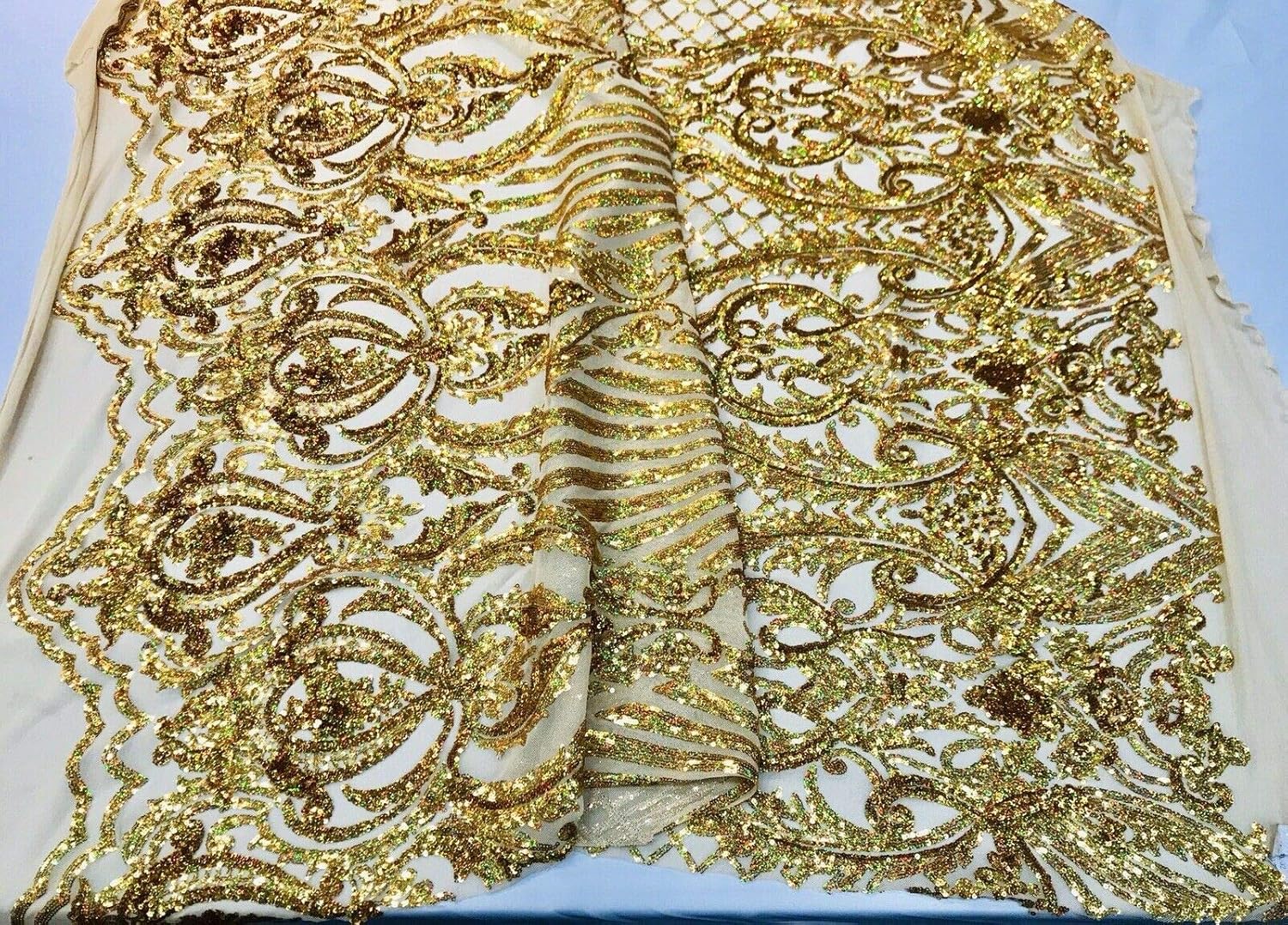 Diseño de lentejuelas de damasco iridiscente dorado en una malla elástica de 4 vías por yarda.